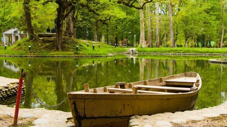 A boat is moored on a pond surrounded by lush greenery of Zugdidi Botanical Garden in Zugdidi, Georgia. Take a tour of Zugdidi Boatanical Garden during your 9 days in Georgia.