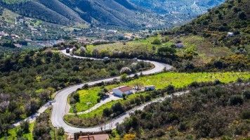 Scenic view of hairpin road against green hills and small villages