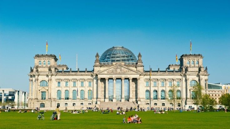 People bask in the sun outside Reichstag building in Berlin, Germany.