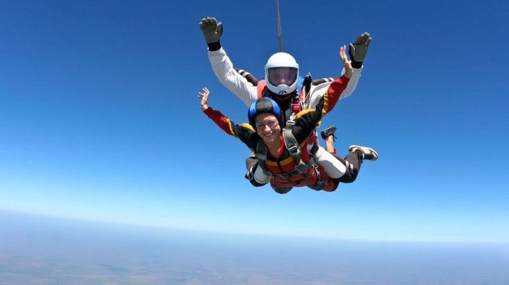 A woman enjoys the thrill of free fall during a tandem skydiving jump.