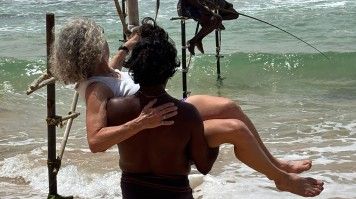 Michelle is carried by a Sri Lankan fisherman towards the fishing poles