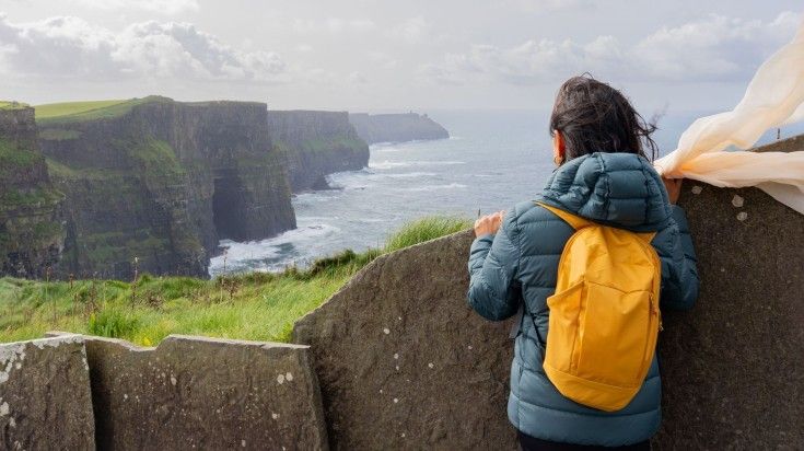 A young woman looking at the beauty of Cliffs of Moher.