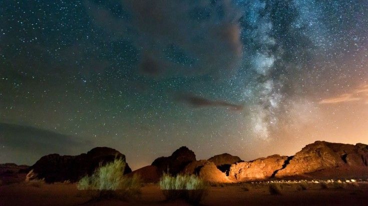 Night view of a desert with rocky mountains and star-filled sky