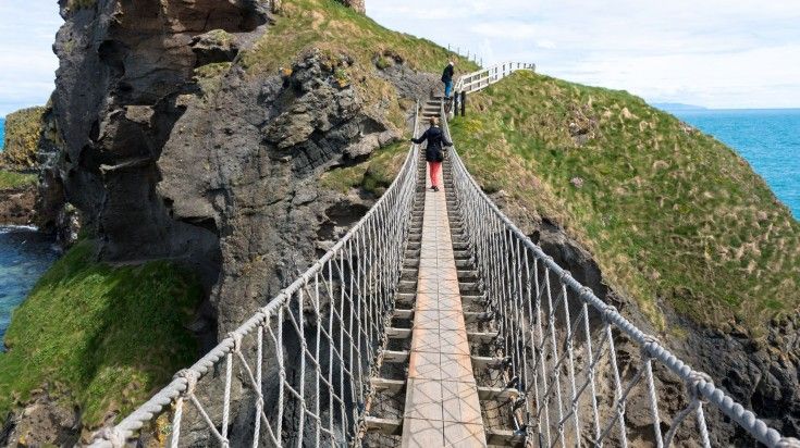 People walking in Carrick-Redde-Rode bridge on a clear day in Ireland. People walking in Carrick-Redde-Rode bridge on a clear day in Ireland.