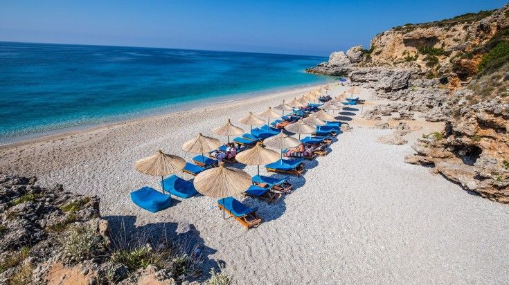 The view of Dhermi Beach with seats on a clear day.