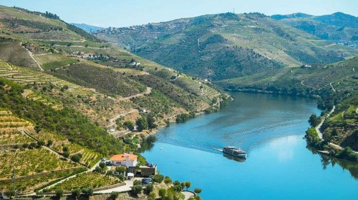 A cruise ship on the Douro River that flows through lush Douro Valley A cruise ship on the Douro River that flows through lush Douro Valley