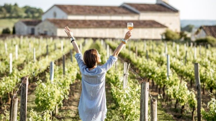 Woman with wine in hand in a vineyard in Bordeaux, France