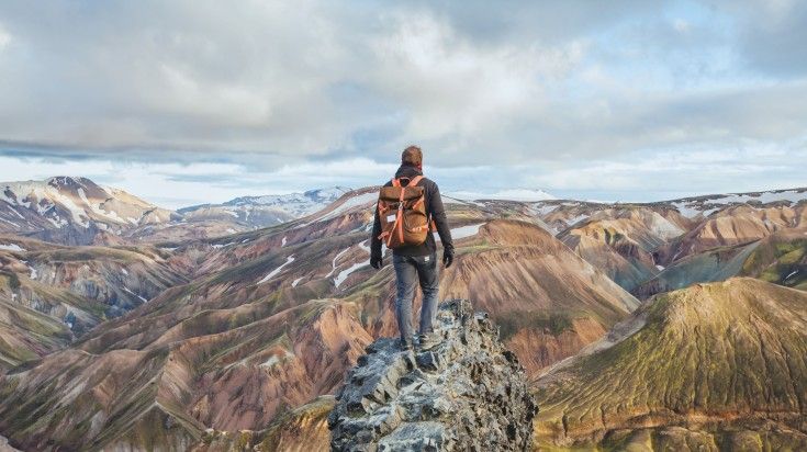Hiker taking in the beauty of Landmannalaugar from atop a cliff. Hiker taking in the beauty of Landmannalaugar from atop a cliff.