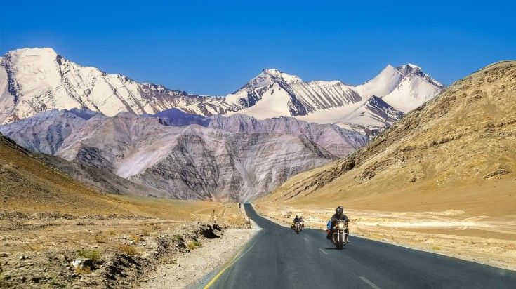 Tourists riding their bikes on national highway with mountains in the distance at Ladakh in India.