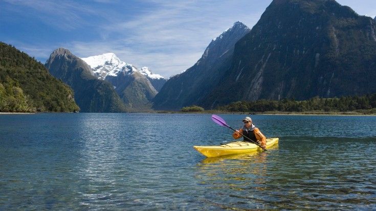 A man kayaking in Te Whanganui-A-Hei Marine Reserve in New Zealand.