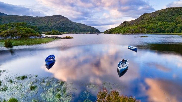 Boats on water in Killarney National Park during dusk in Ireland.