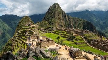 Machu Picchu ruins with tourists with dramatic clouds.