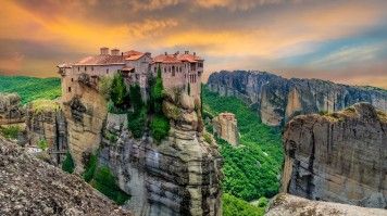 Visit Meteora Monastery in Greece and marvel at its breathtaking cliffs and ancient spiritual heritage. Meterora monastery during dusk on your 6 days in Greece.