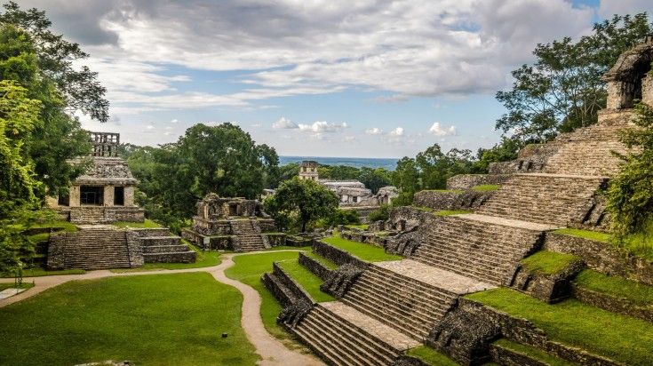 Temples of the Cross Group at mayan ruins surrounded by trees in Mexico on a cloudy day.