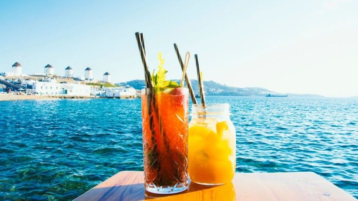 Two cocktails on the table with a view of  Mykonos in Greece.