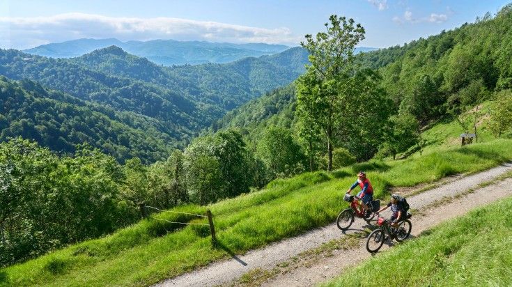 The wonderful landscapes of Slovenia are best experienced on a cycling tour. Two tourists cycling in the in the Karst green mountains of Slovenia.