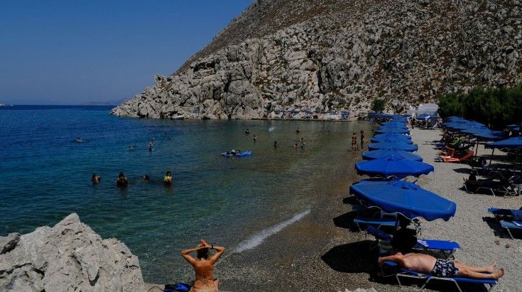 A girl enjoying in Saint Nicholas Beach of Symi Island. People enjoy the sea in Saint Nicholas Beach of Symi Island.