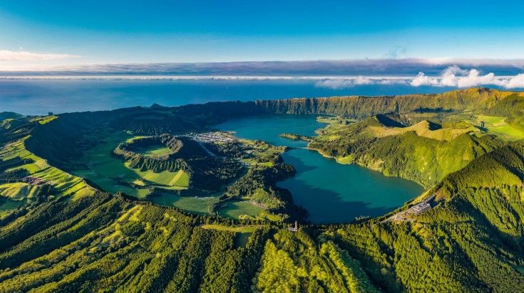 Aerial view of lake surrounded by lush green forest in the hills of Azores Sao Miguel in Portugal, one of the best places to visit in May.