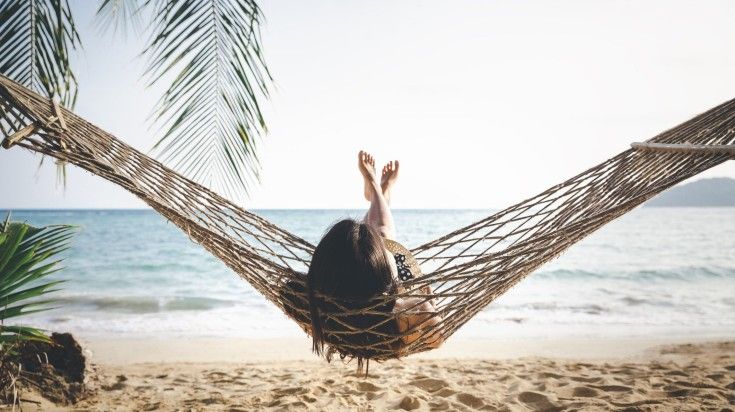 A girl relaxing in hammock on Koh Samui beach during evening in Thailand.