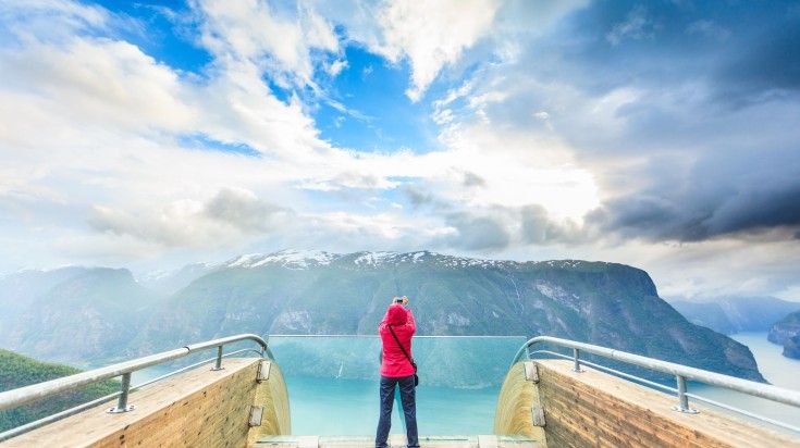 A tourist woman capturing the beauty of the Norwegian landscape fromStegast