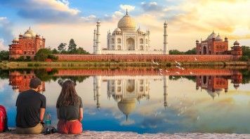 A tourist couple admiring the beauty of Taj Mahal during dusk.
