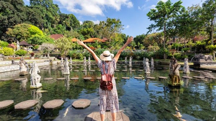 A hiker with open arms in Tirtagangga on a clear day.