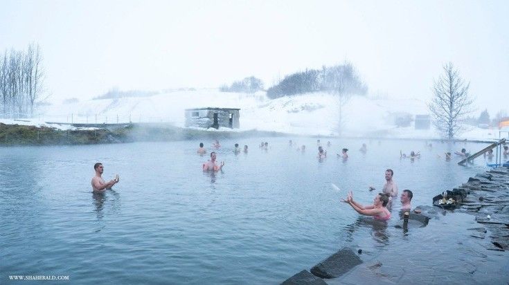 Tourists swimming in the waters of Secret Lagoon.
