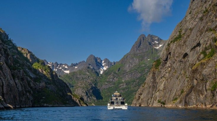 A cruise between the steeped sided mountain on a clear day in Trollfjord.