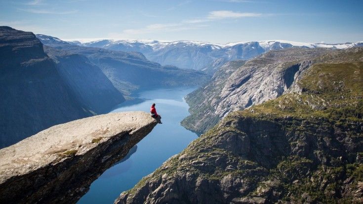 A hiker at sitting at the top of the rock and admiring the beauty of Trollt