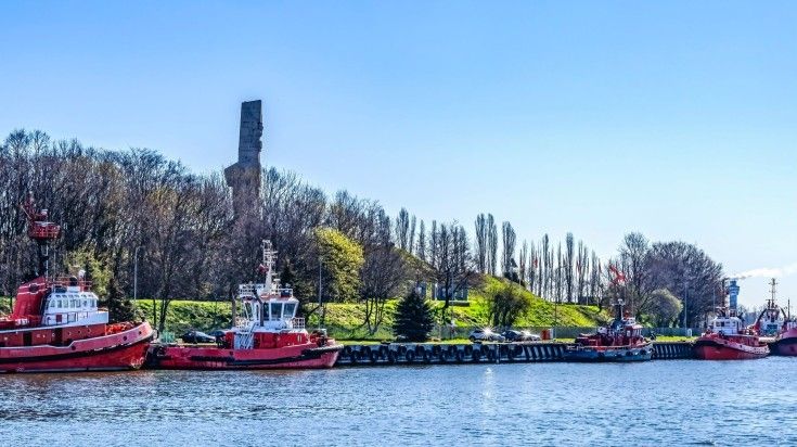 Tugboats at the Westerplatte Monument on a sunny day.