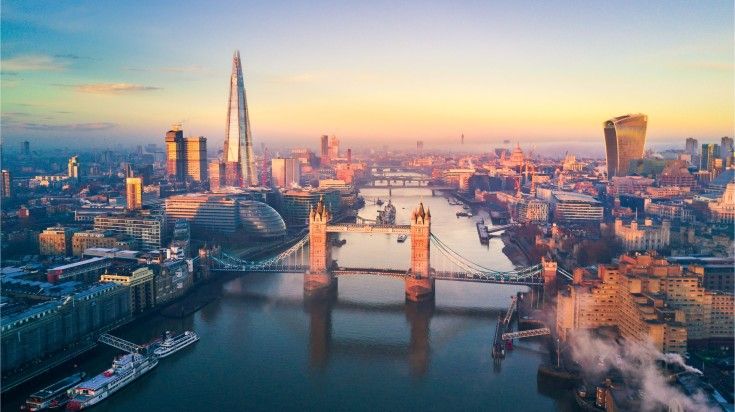 Aerial view of London at dawn with the River Thames, Tower Bridge, the Shard, and the Walkie Talkie building under a clear sky—some of the best places to visit in September.