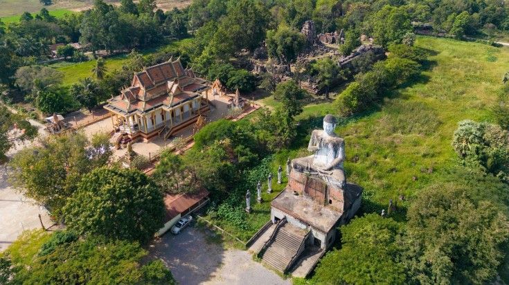 Wat Ek Phnom Temple and Buddha statue surrounded by lush greenery in Battam