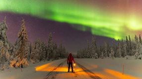 A man with lantern admiring the Northern Lights in Lapland.