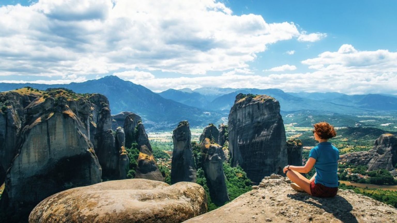Explore Meteora during your 10 days in Greece and marvel at the awe-inspiring monasteries perched atop towering rock formations A tourist girl sitting and admiring the beauty of Meteora during her 10 days in Greece.