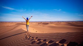 A woman tourist with open arms in the sand dune in the Sahara Desert on her 10 days in Morocco.