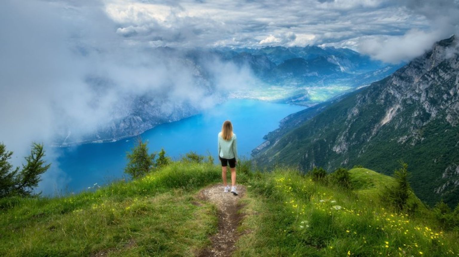 Immerse yourself in the serene beauty of Lake Garda during your 12 days in Europe, where crystal-clear waters and charming villages await. A girl admiring the beauty of Lake Grada during her 12 days in Europe trip.