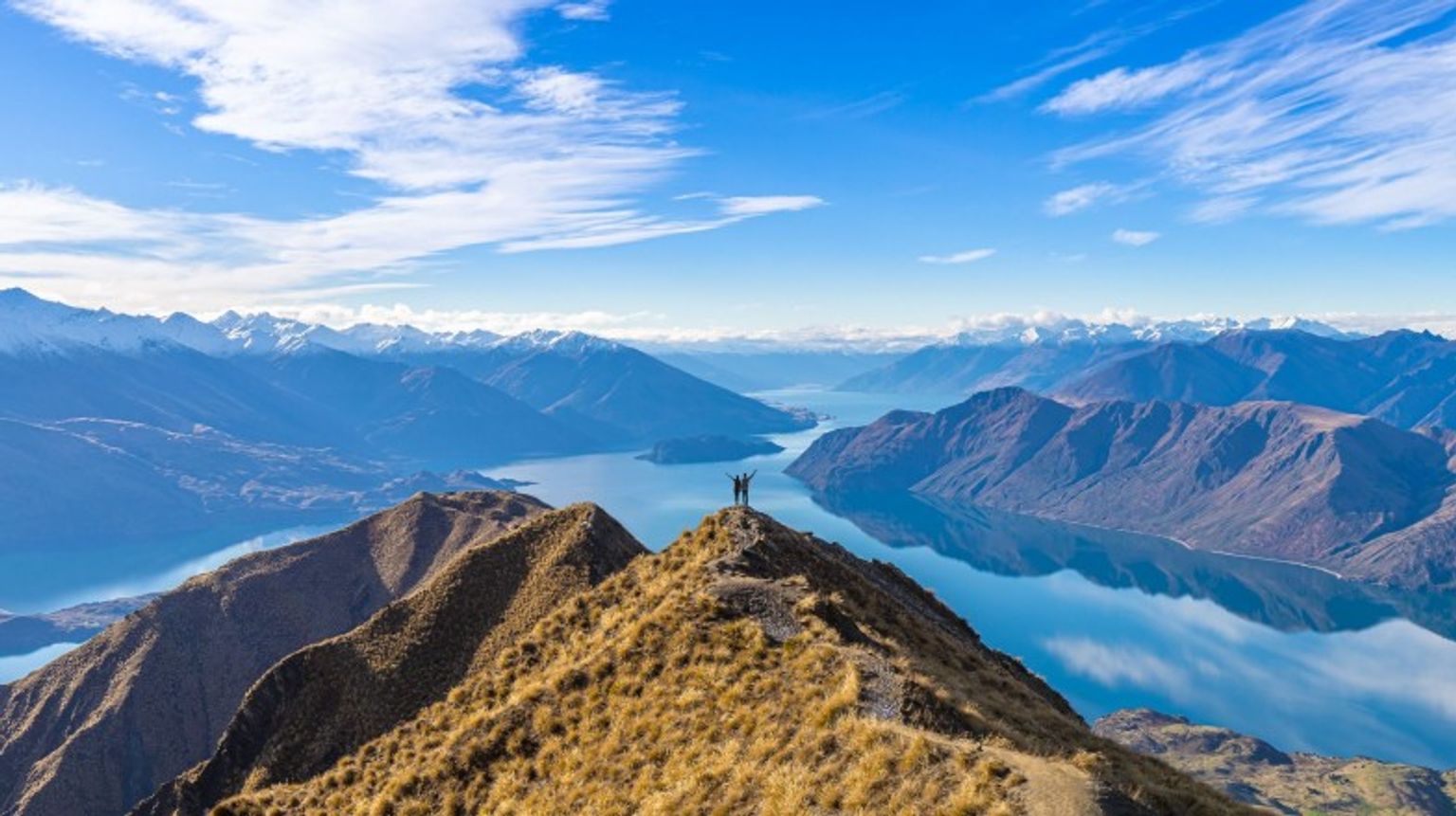 Young Asian couple with open arms at Roy's Peak in Wanaka during their 12 days in New Zealand.