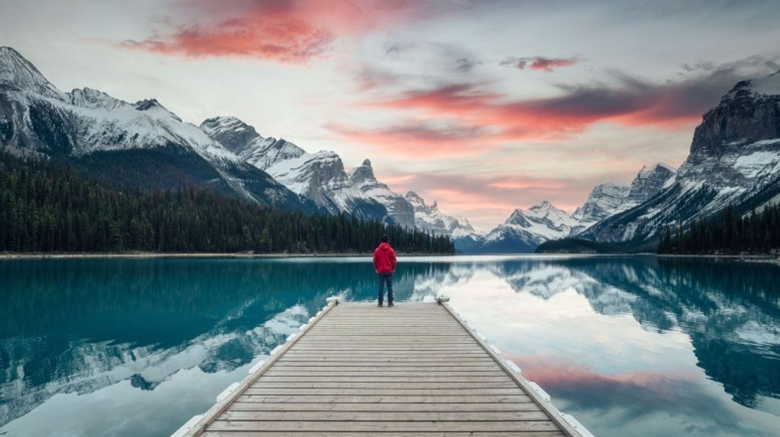 The scenery of Spirit Island where a male traveler admires the beauty of sunset in Magline Lake in Jasper National Park on his 2 weeks in Canada.