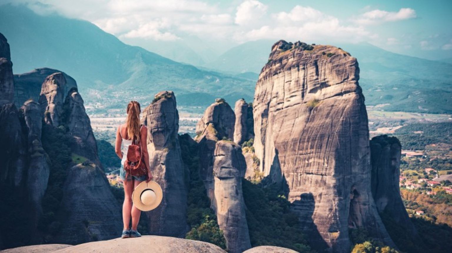 A young woman standing on the cliff enjoying the beautiful view of Meteora mountain during her 2 weeks in Greece.