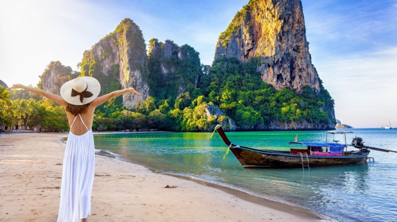 A tourist girl with open arms on Krabi beach during sunset on her 3 weeks in Thailand.