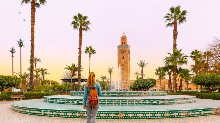 A woman tourist looking at Koutoubia mosque during dusk on her 4 days in Morocco.