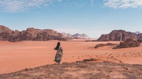 A woman standing on a top of mountain and enjoying the landscape of Wadi Rum desert during her 5 days in Jordan.