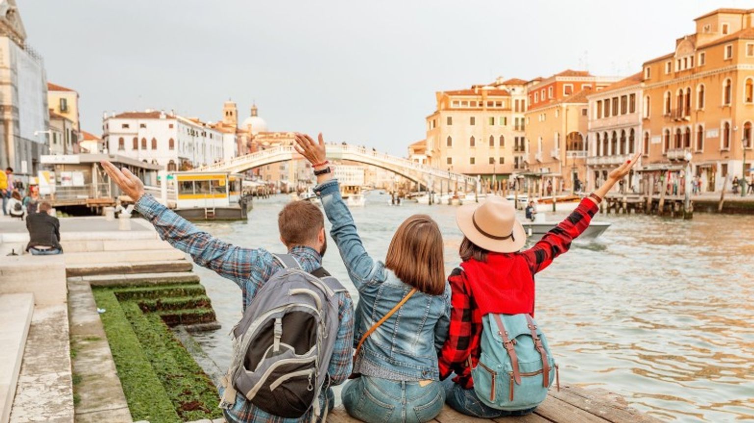 A group of friends posing in front of Venice canal during their 6 days in Italy.