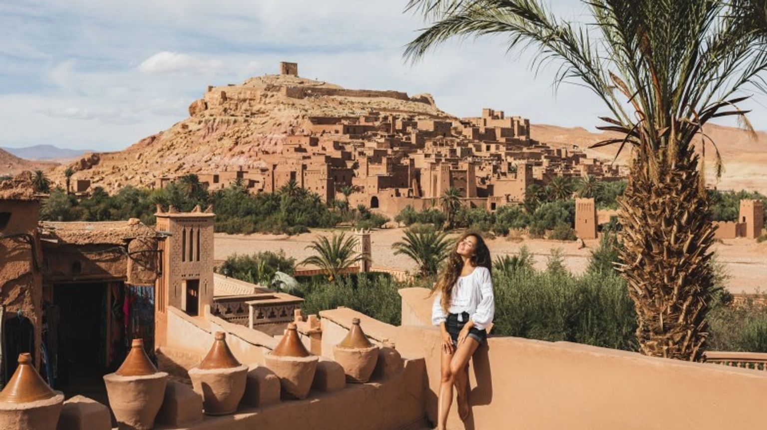 A happy tourist girl posing in front of Ait-Ben-Haddou during her 8 days in Morocco.