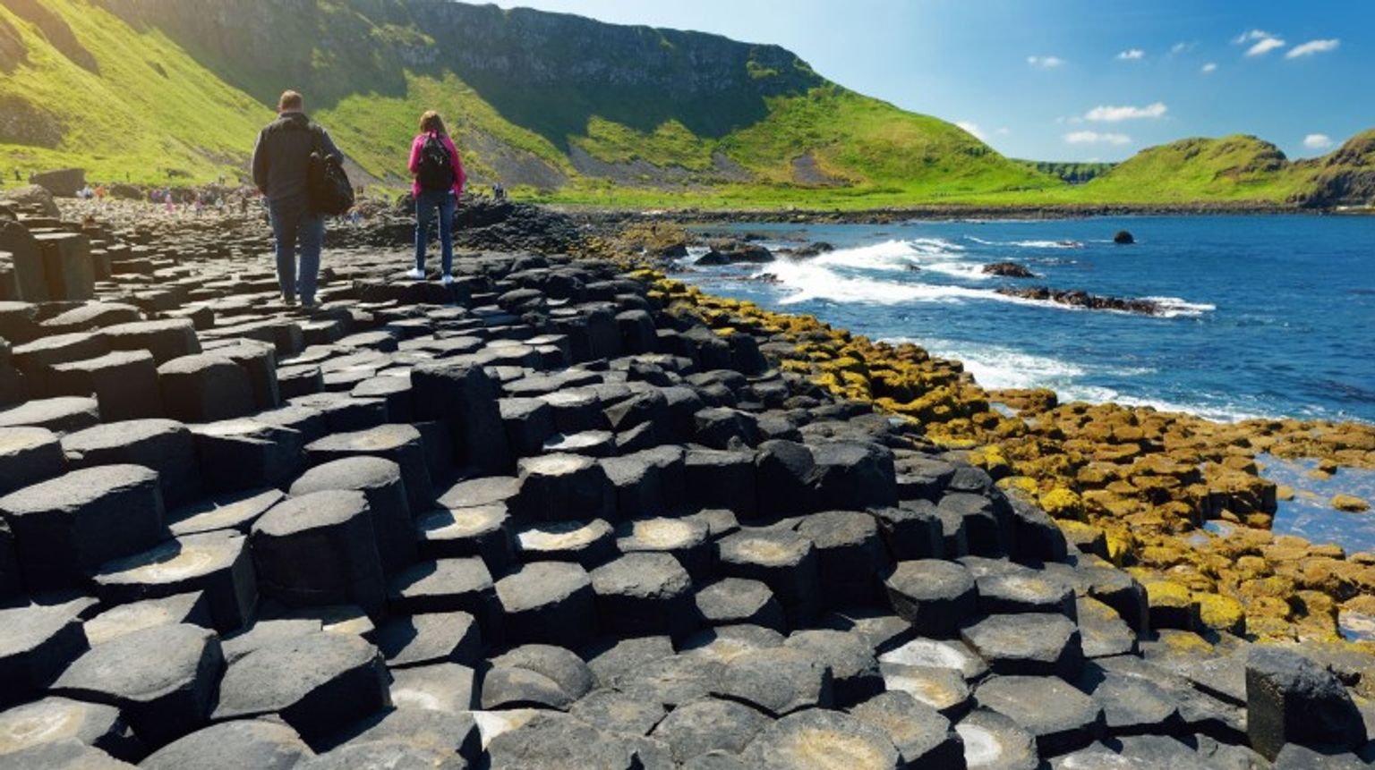 Two tourists walking in the Giant's Causeway on a clear day during their 9 days in Ireland tour.