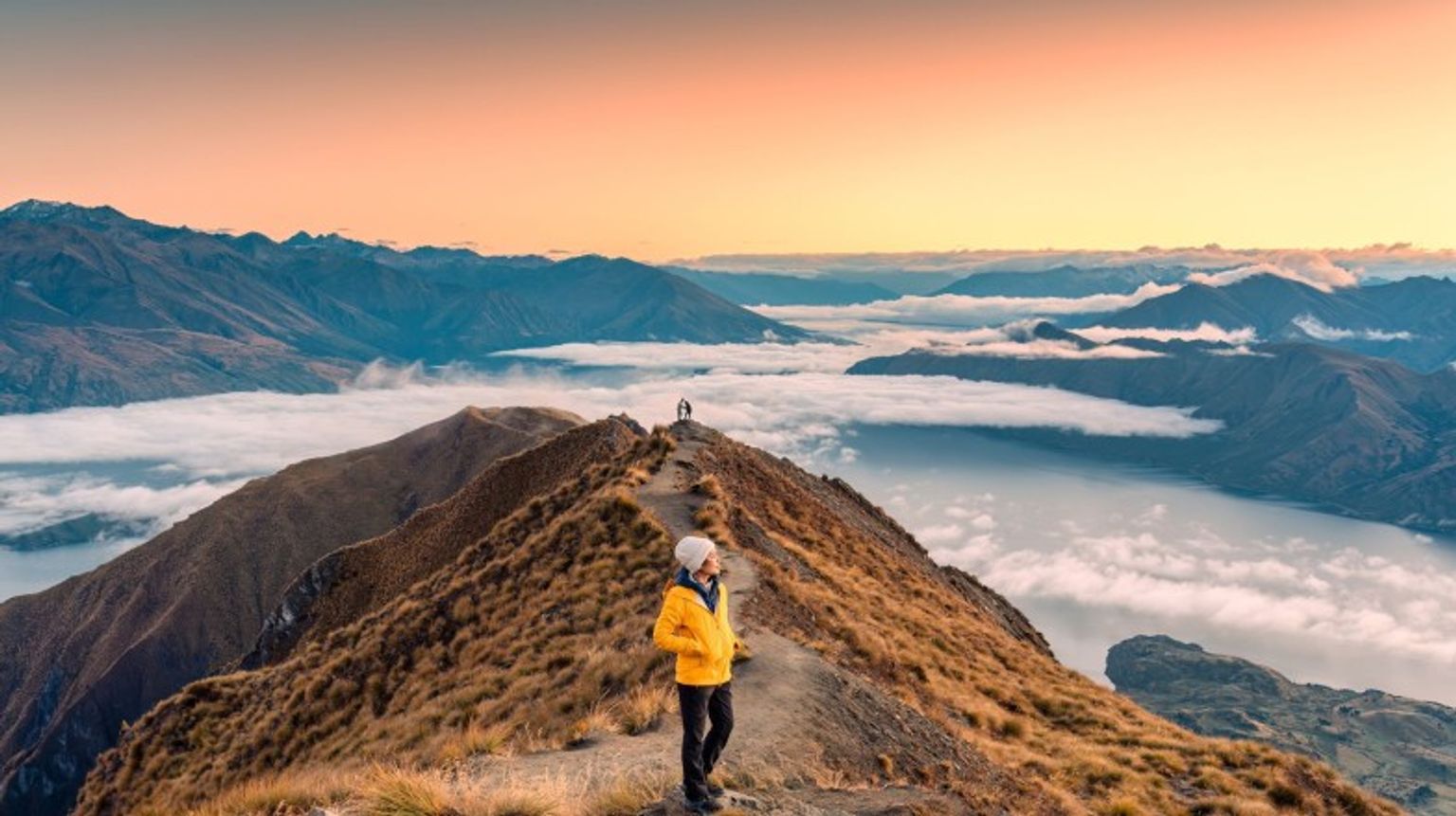 An Asian hiker woman standing on Roys peak Pointview with sunrise and fog on Wakana; how many days to spend in New Zealand.