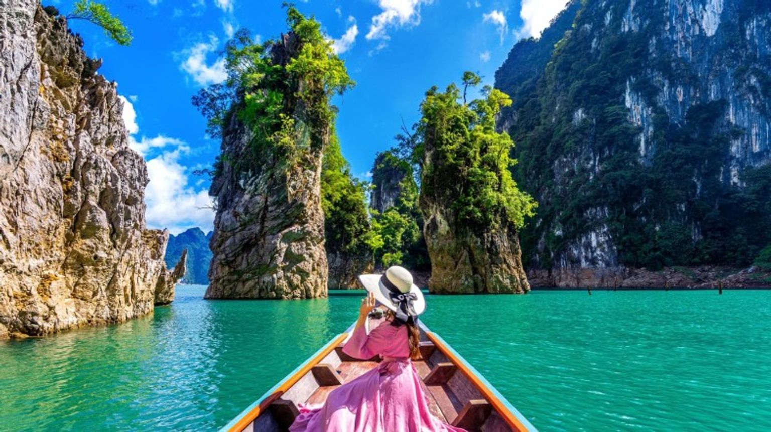 If you're wondering how many days to spend in Thailand, 10 days is ideal for experiencing its vibrant cities, serene beaches, and rich cultural sites. A girl in the boat in Khao National Park on a clear day; how many days to spend in Thailand.