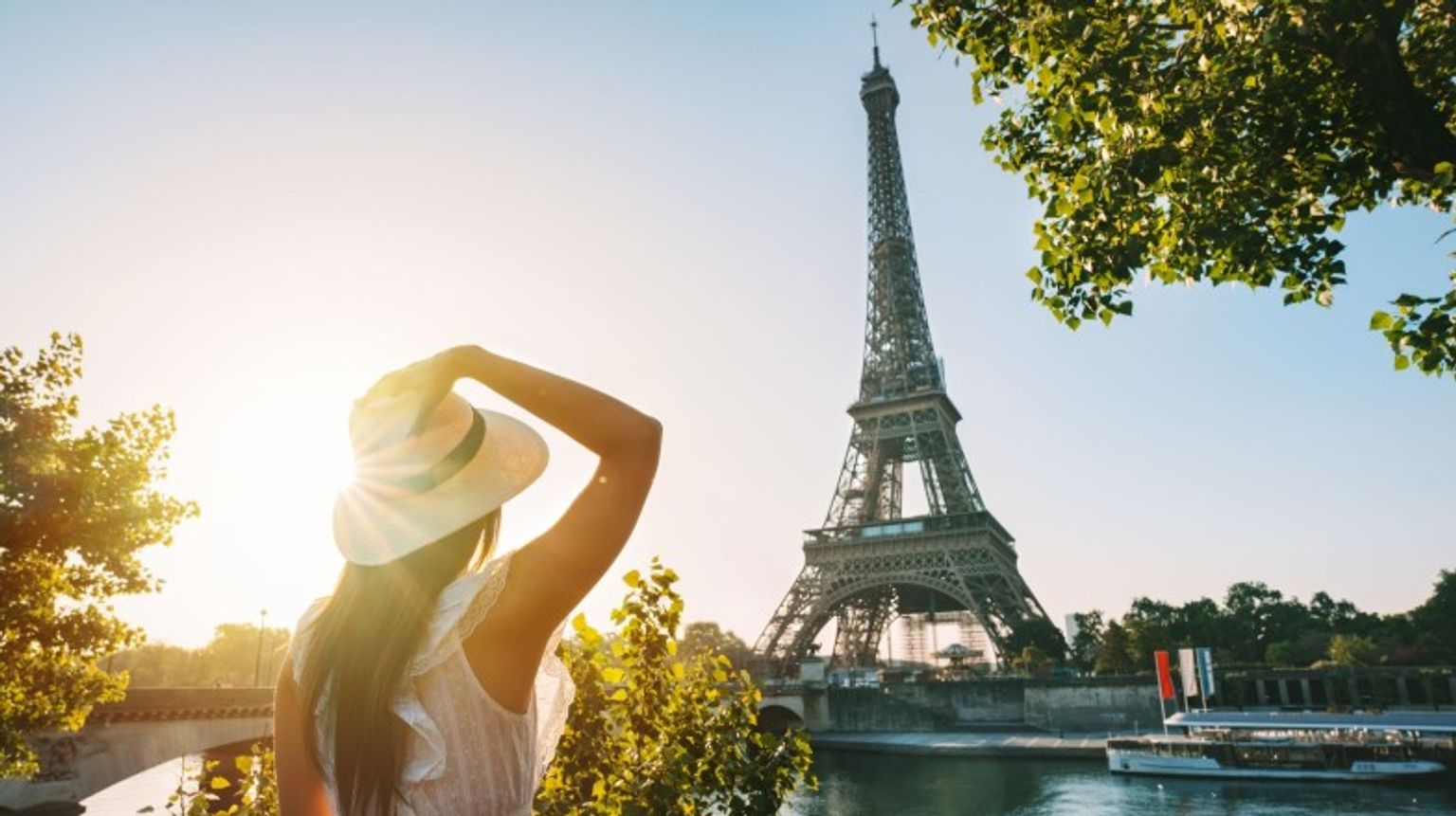 A young tourist girl admiring the beauty of the Eiffel Tower during sunset on her one week in Europe.