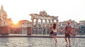 A couple walking towards Roman Forum at sunrise during their one week in Italy trip.
