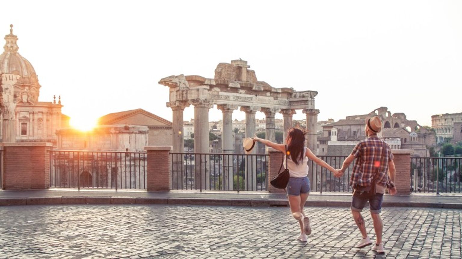 A couple walking towards Roman Forum at sunrise during their one week in Italy trip.